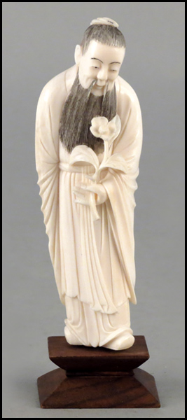 CARVED IVORY FIGURE HOLDING A FLOWER.