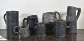 SEVEN EARLY LEATHER TANKARDS AND POURING