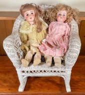 Two bisque head dolls in white wicker