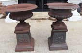 A VINTAGE PAIR OF CAST IRON URNS ON