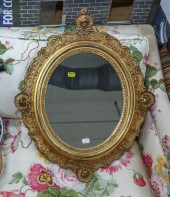 AN OVAL MIRROR IN ANTIQUE GILT FRAME